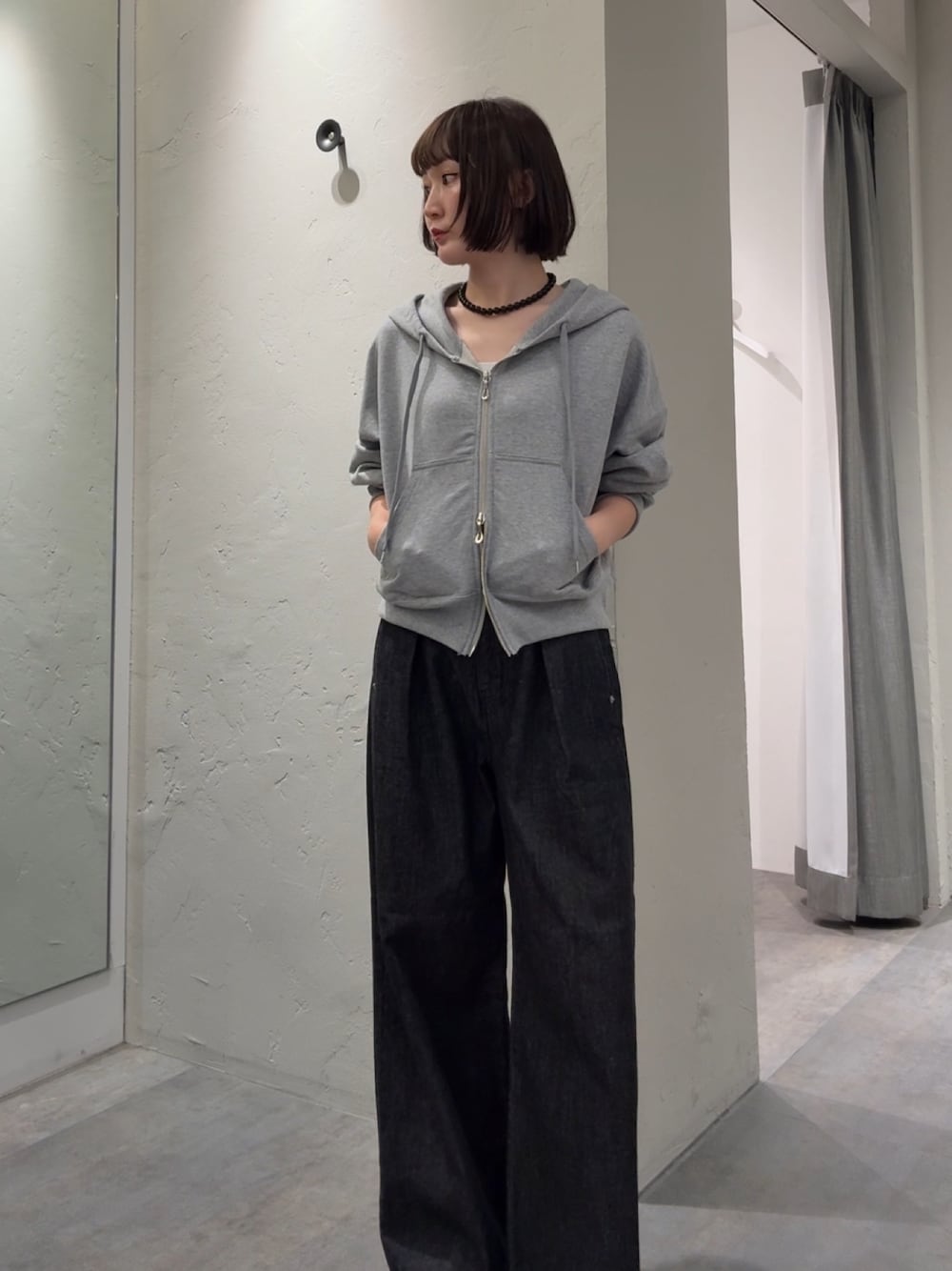 グレー系のパーカー、ブラック系のデニムパンツを着用したレディースの秋コーディネートの1枚目の写真