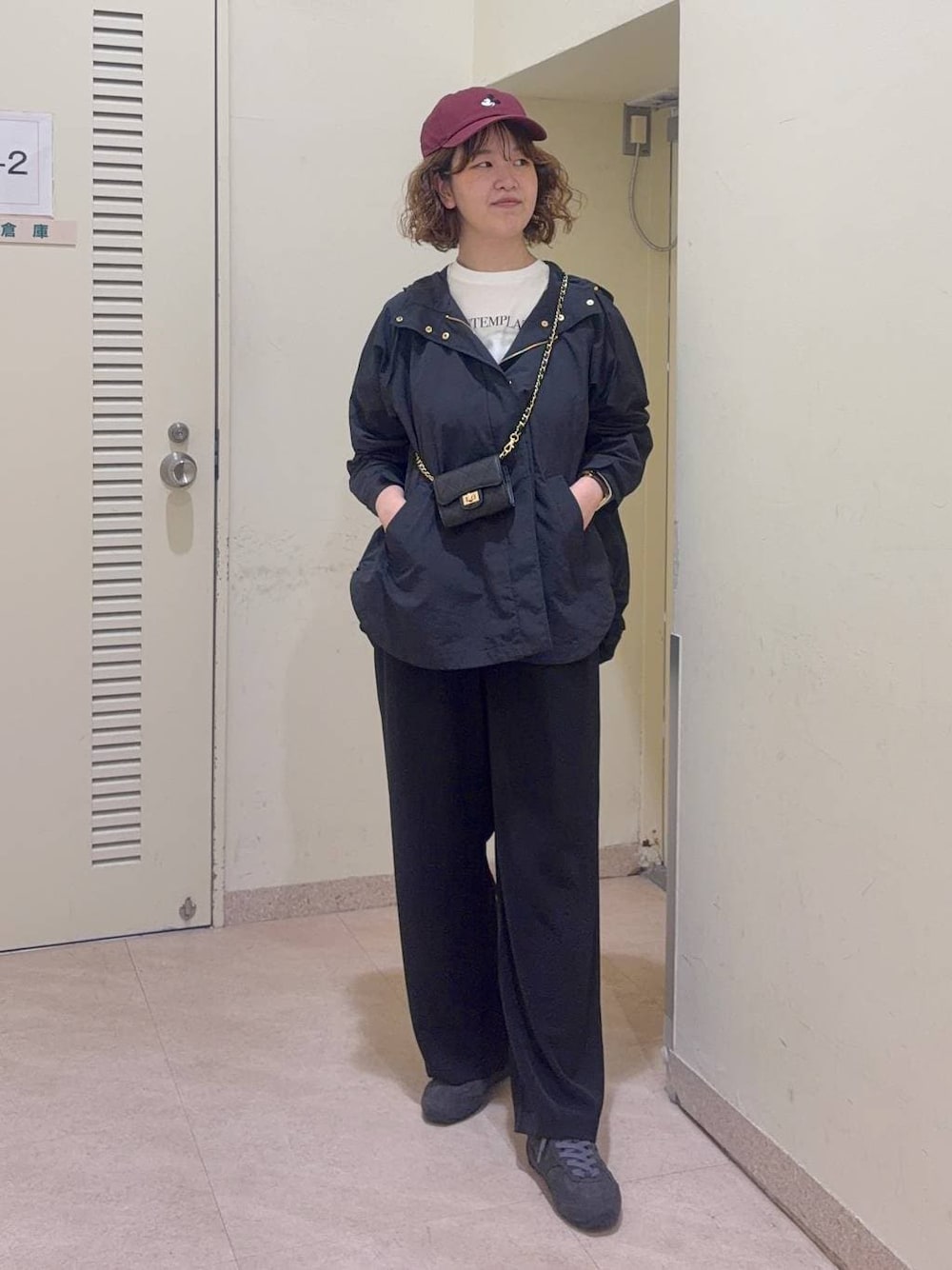 ブラック系のスラックス、ホワイト系のTシャツ/カットソー、ブラック系のマウンテンパーカーを着用したレディースの冬コーディネートの1枚目の写真