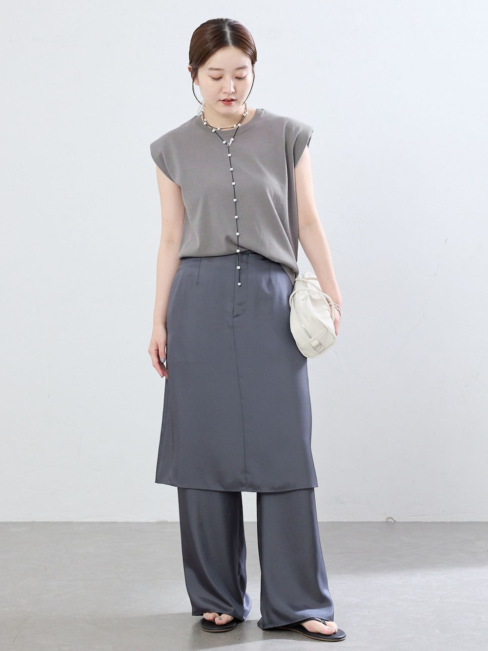 グレー系のその他パンツ、グレー系のニット/セーター、ブラック系のサンダルを着用したレディースの夏コーディネートの1枚目の写真