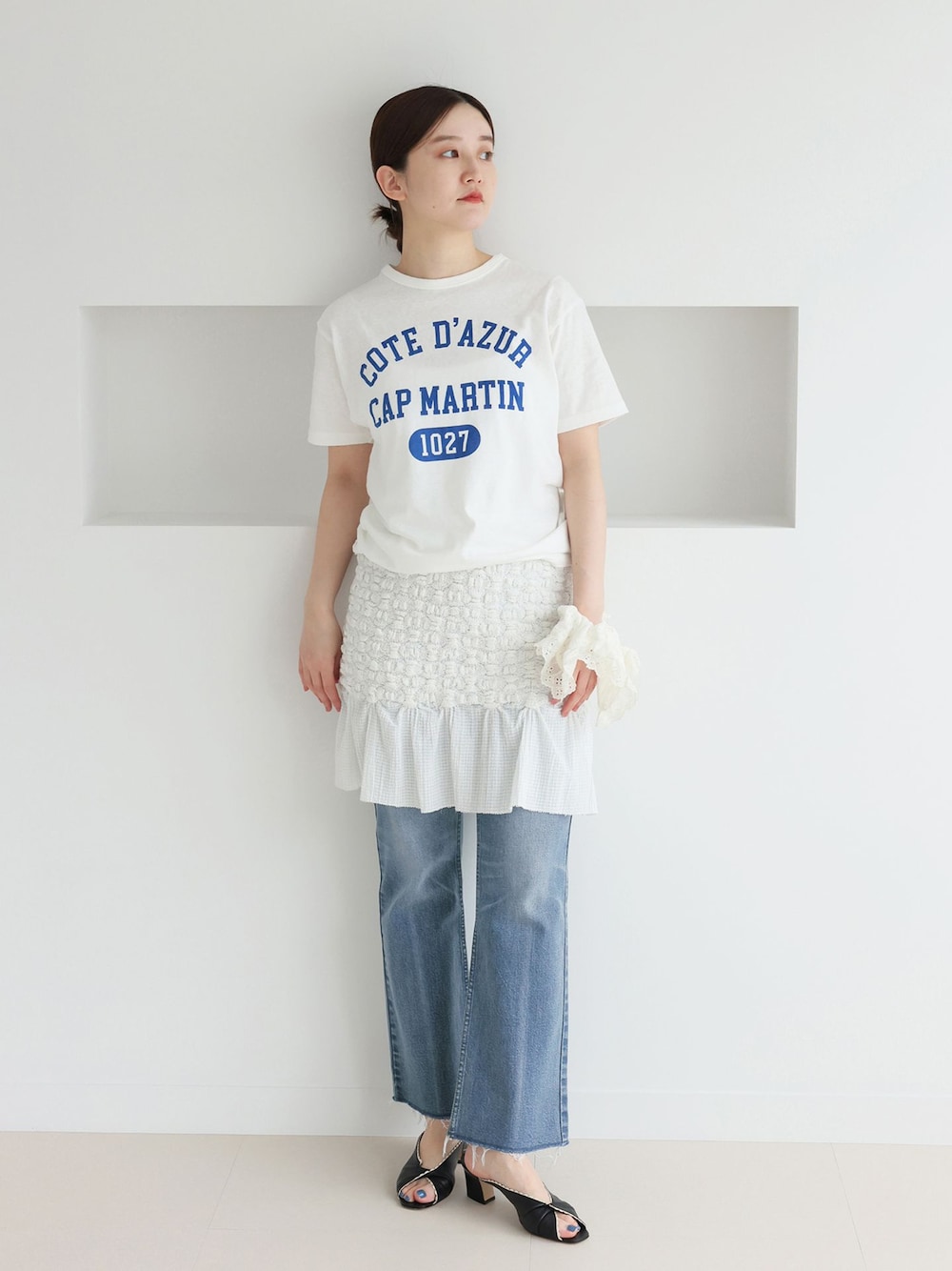 ブルー系のデニムパンツ、ホワイト系のスカート、ホワイト系のTシャツ/カットソーを着用したレディースの春コーディネートの1枚目の写真