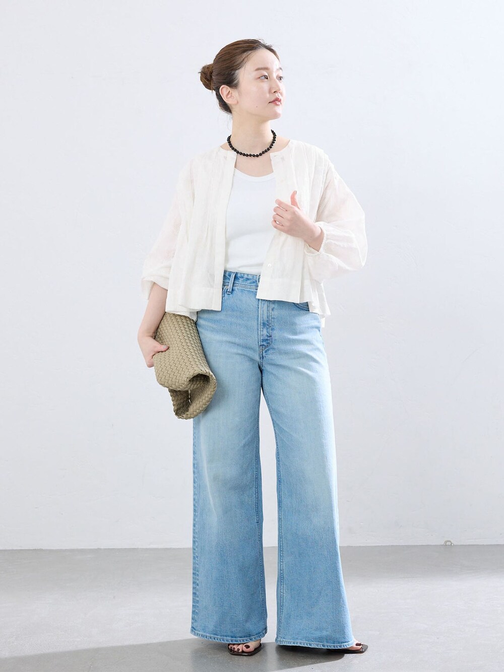 ブルー系のデニムパンツ、ベージュ系のトートバッグ、ブラック系のネックレスを着用したレディースの夏コーディネートの1枚目の写真