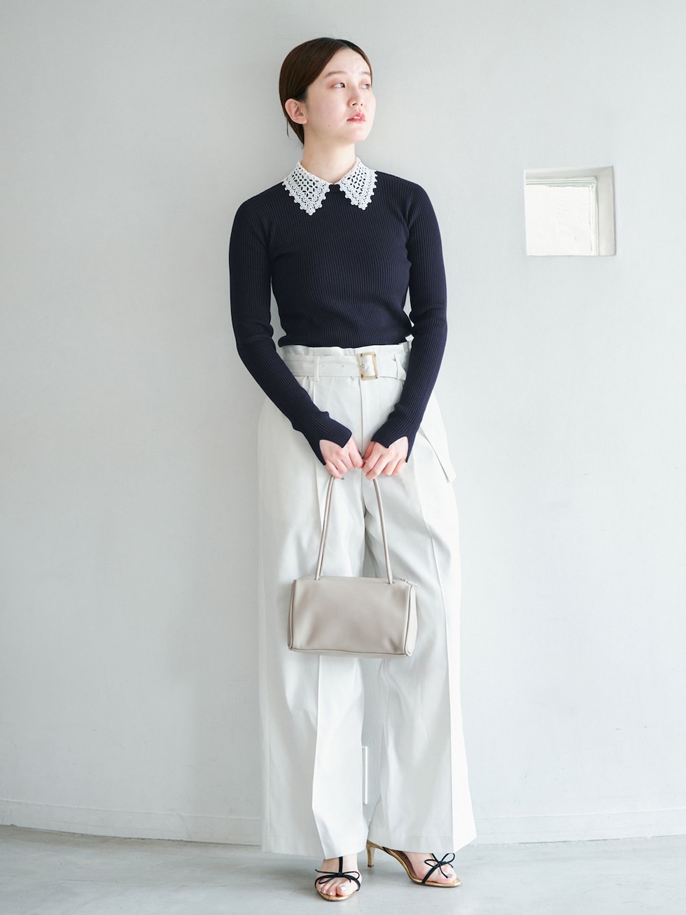 ホワイト系のチノパンツ、ブルー系のニット/セーター、イエロー系のショルダーバッグを着用したレディースの冬コーディネートの1枚目の写真
