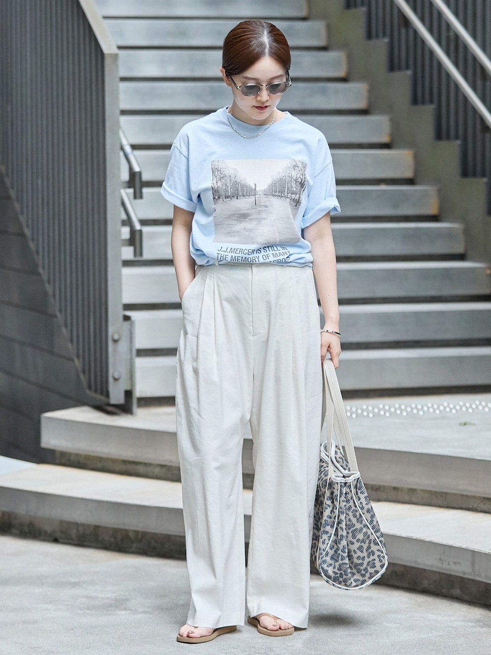 ホワイト系のスラックス、ブルー系のTシャツ/カットソー、ブラウン系のトートバッグを着用したレディースの秋コーディネートの1枚目の写真
