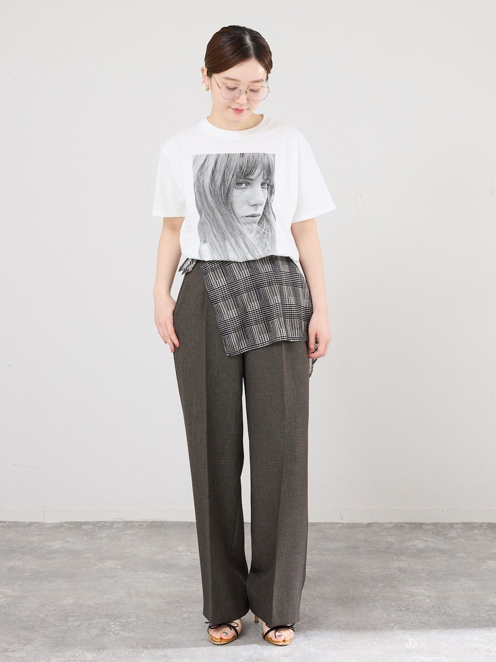 ブラウン系のスラックス、ホワイト系のTシャツ/カットソー、ブラック系のサンダルを着用したレディースの春コーディネートの1枚目の写真