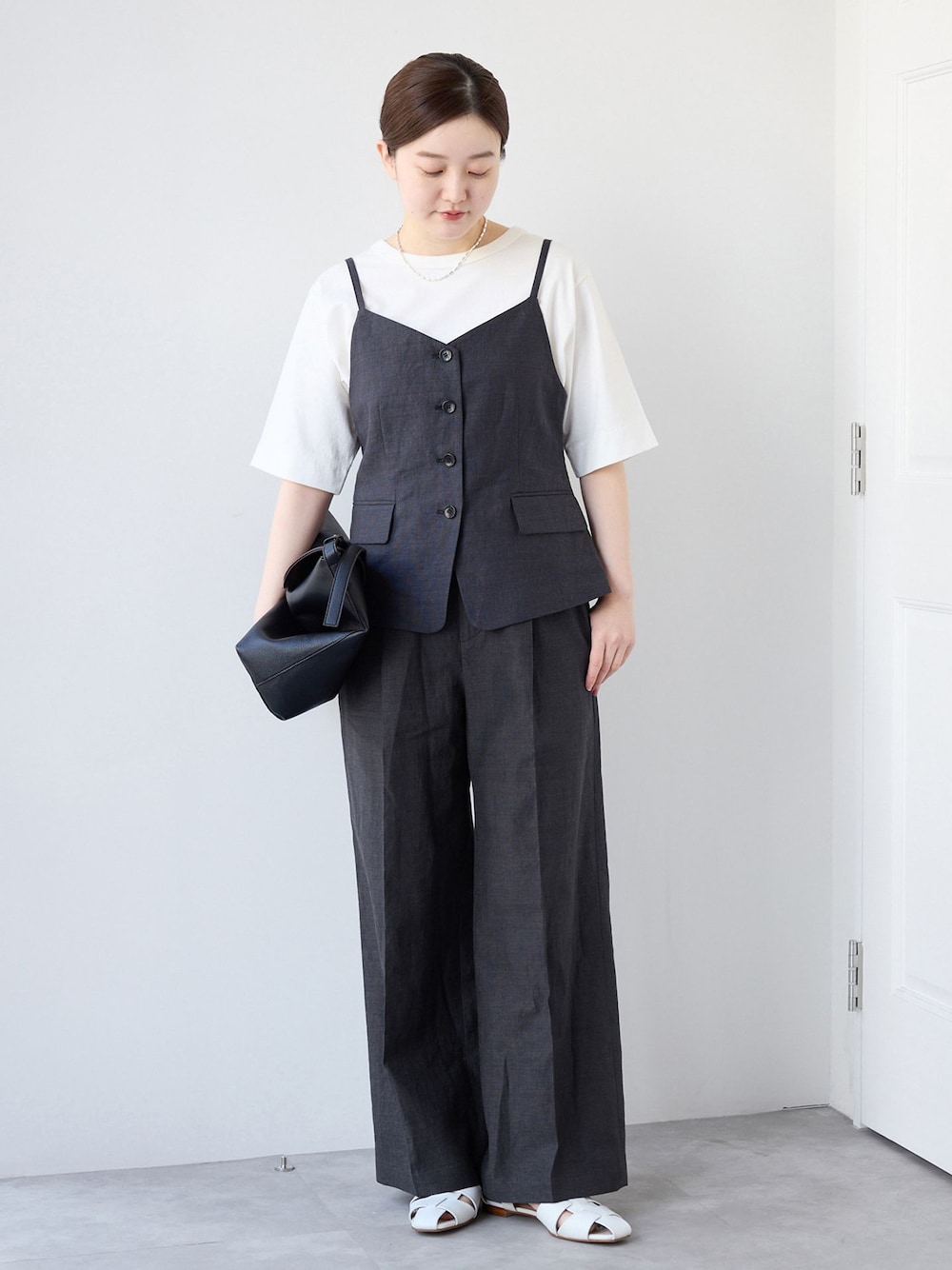 ブラック系のベスト、ブラック系のスラックス、ホワイト系のTシャツ/カットソーを着用したレディースの春コーディネートの1枚目の写真