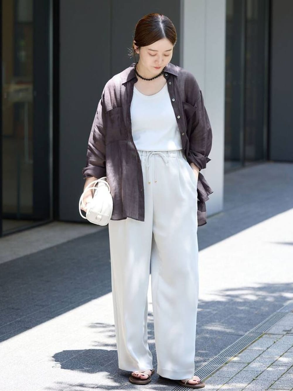 ベージュ系のその他パンツ、ブラック系のシャツ/ブラウス、ホワイト系のショルダーバッグを着用したレディースの春コーディネートの1枚目の写真