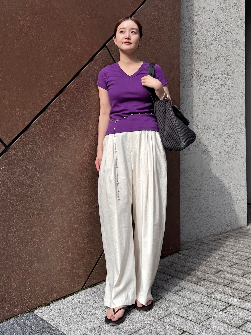 ホワイト系のスラックス、パープル系のTシャツ/カットソー、ブラック系のサンダルを着用したレディースの夏コーディネートの1枚目の写真