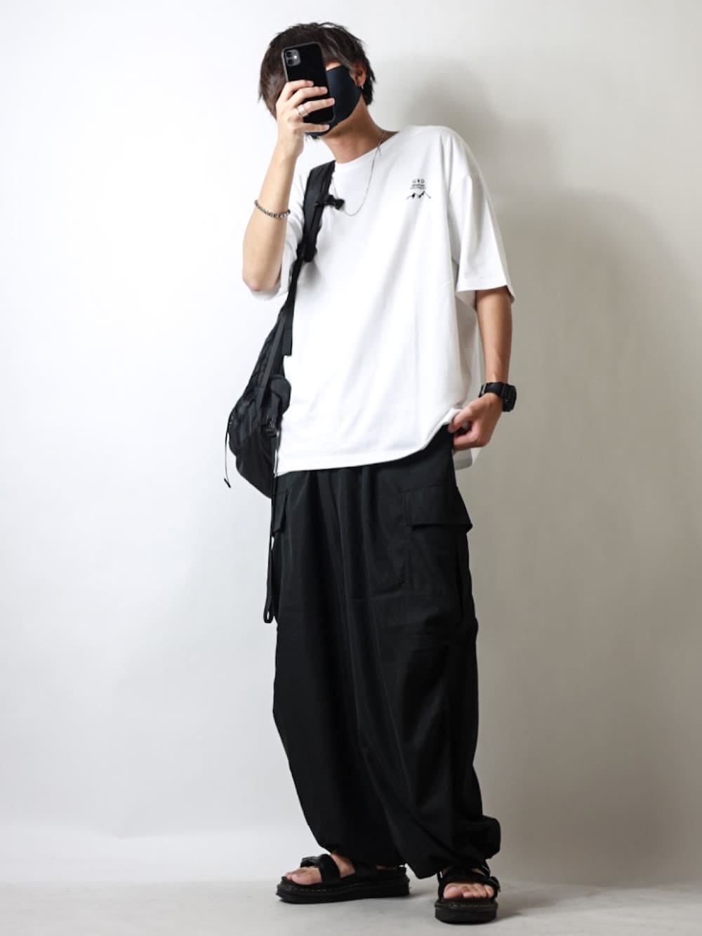 ホワイト系のTシャツ/カットソー、ブラック系のカーゴパンツ、ブラック系のサンダルを着用したメンズの夏コーディネートの1枚目の写真
