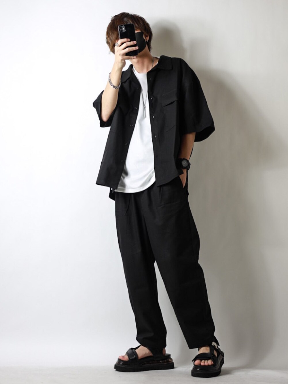 ブラック系のセットアップ、ホワイト系のTシャツ/カットソー、ブラック系のサンダルを着用したメンズの春コーディネートの1枚目の写真