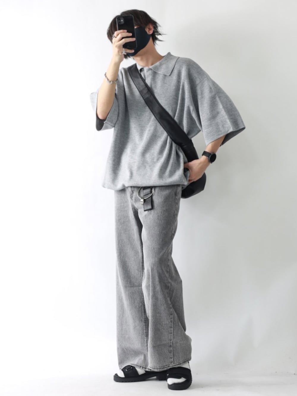 グレー系のポロシャツ、グレー系のデニムパンツ、ブラック系のサンダルを着用したメンズの夏コーディネートの1枚目の写真