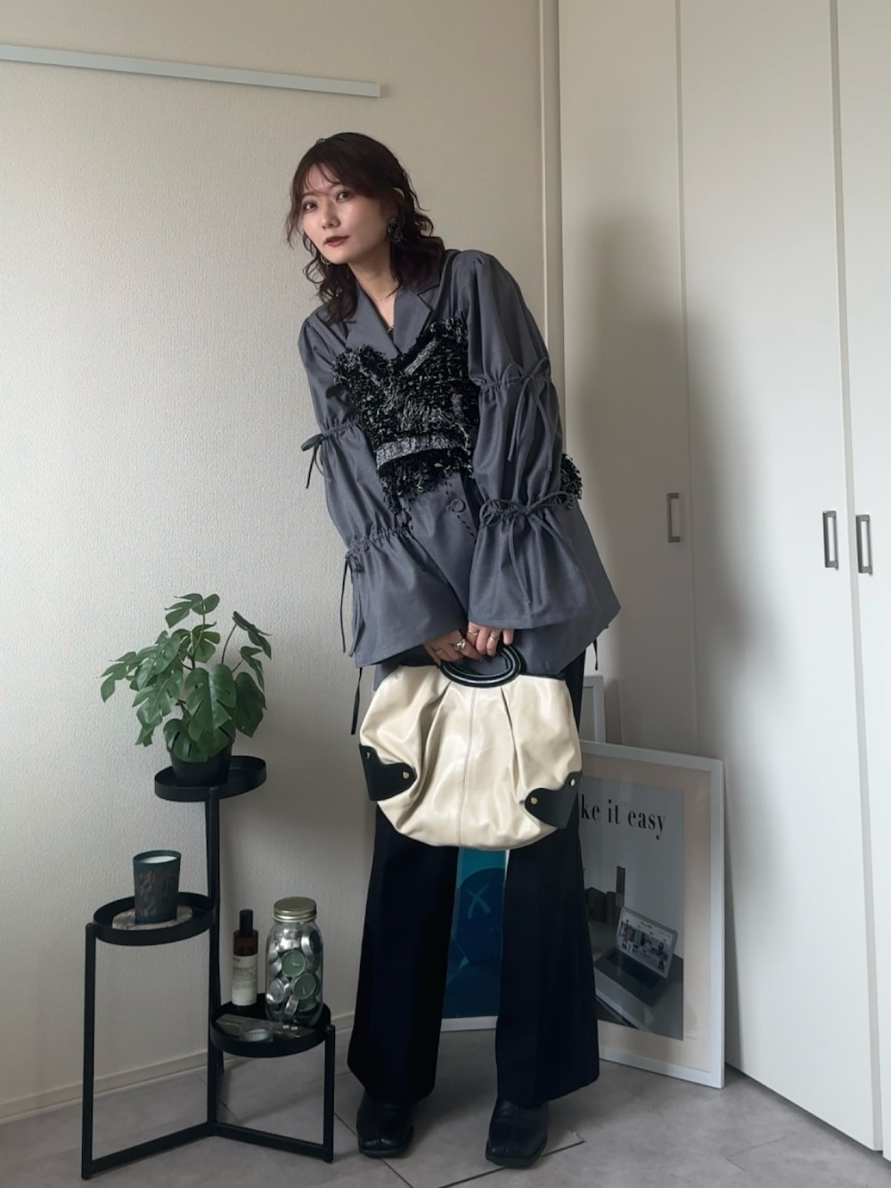 ブラック系のブーツ、ホワイト系のバッグ、ブラック系のベストを着用したレディースの冬コーディネートの1枚目の写真