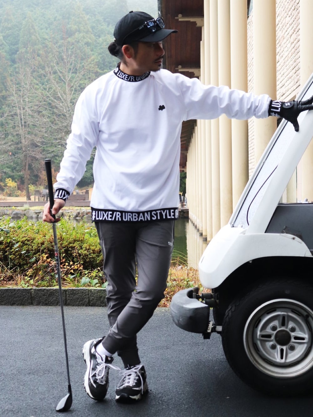 ホワイト系のTシャツ/カットソー、グレー系のチノパンツ、ブラック系のキャップを着用したメンズの冬コーディネートの1枚目の写真