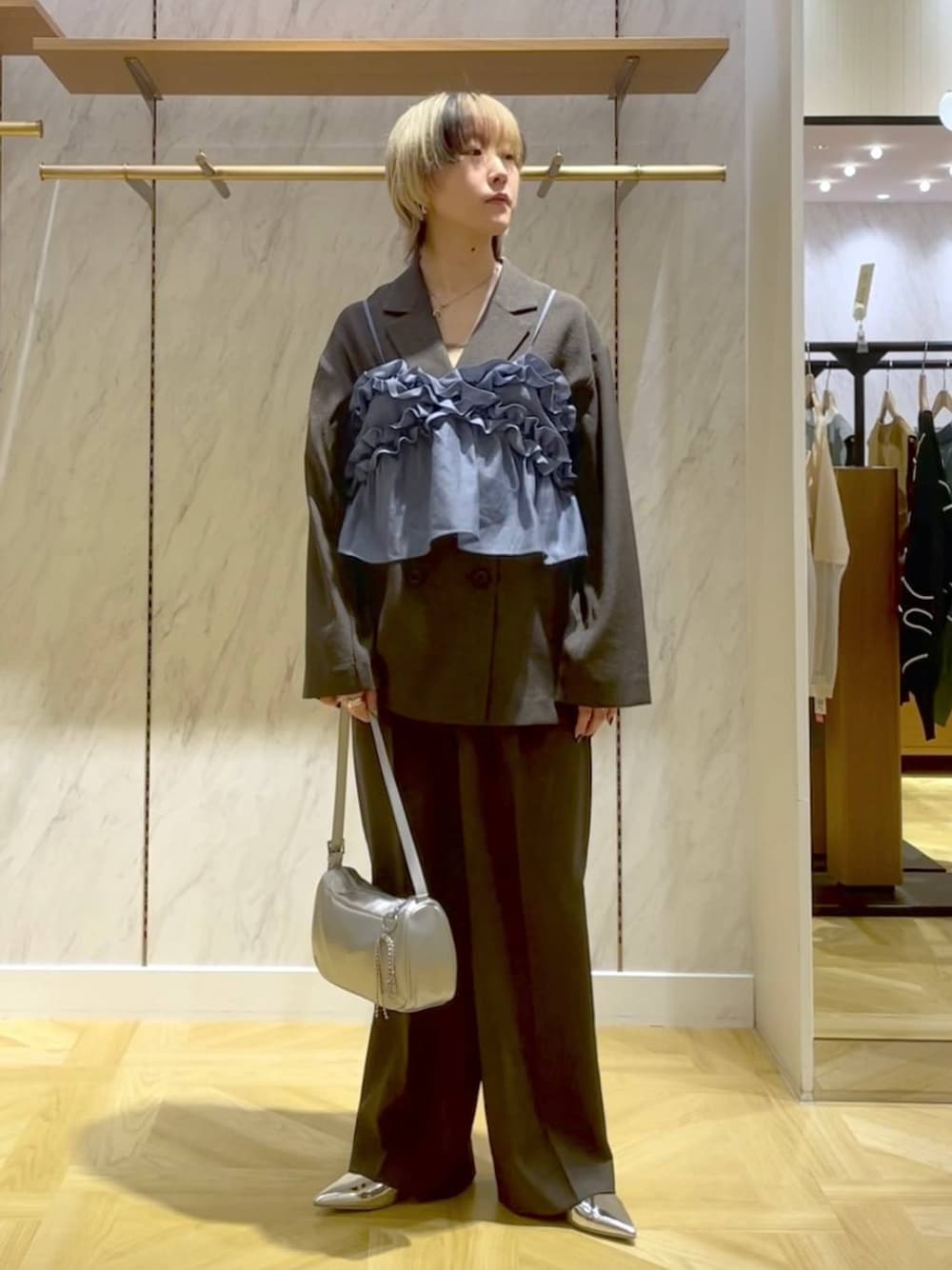 グレー系のスラックス、グレー系のテーラードジャケット、シルバー系のトートバッグを着用したレディースの春コーディネートの1枚目の写真