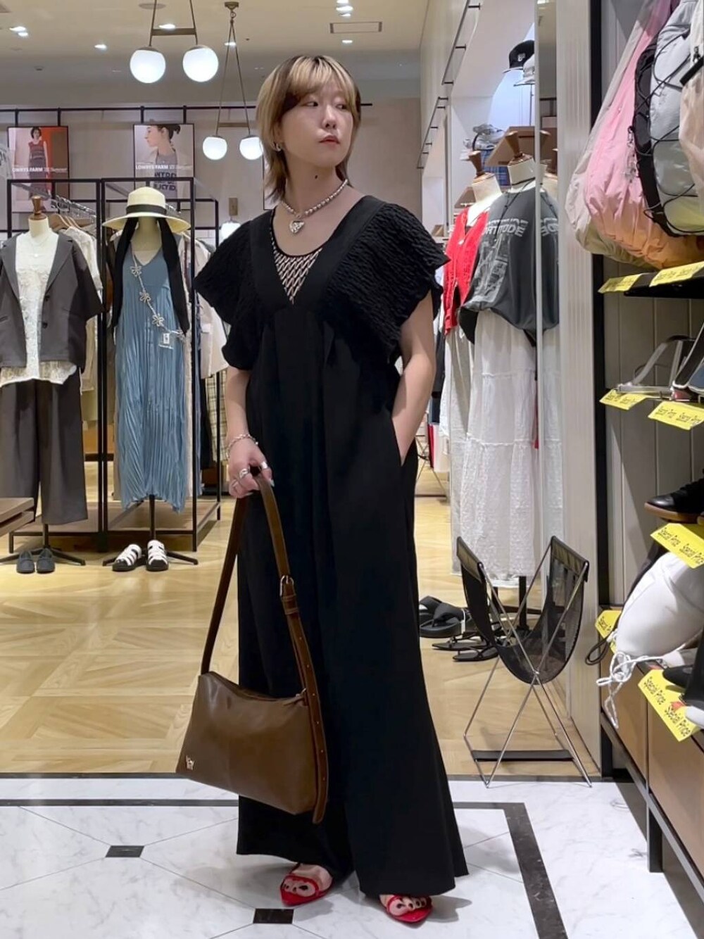 レッド系のサンダル、ブラック系のサロペット/オーバーオール、ブラウン系のショルダーバッグを着用したレディースの春コーディネートの1枚目の写真