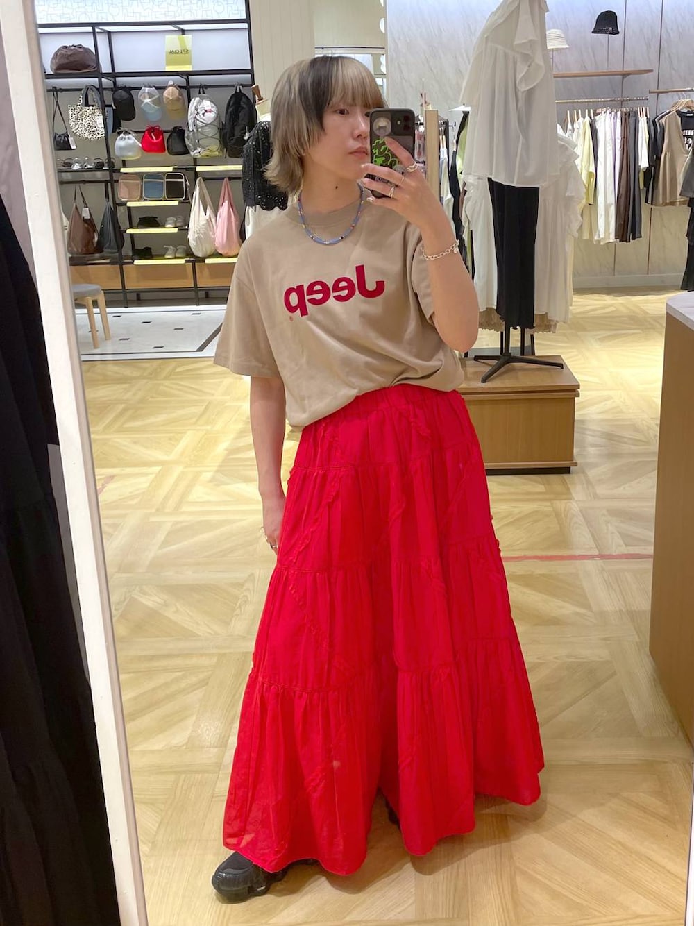 レッド系のスカート、ベージュ系のTシャツ/カットソーを着用したレディースの春コーディネートの1枚目の写真