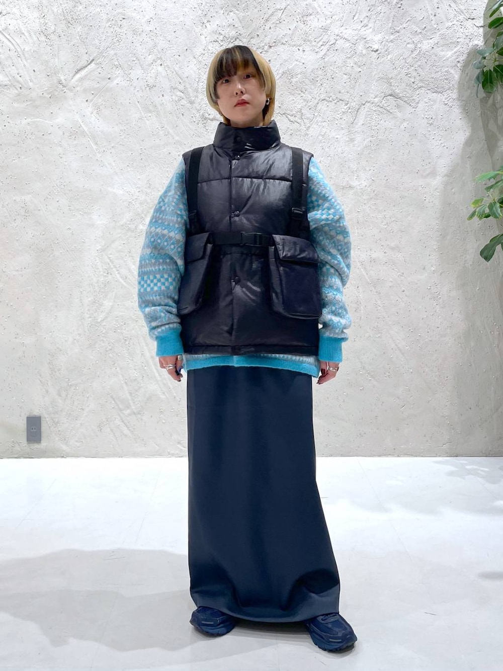 ブルー系のニット/セーター、グリーン系のスカート、ブラック系のダウンベストを着用したレディースの秋コーディネートの1枚目の写真