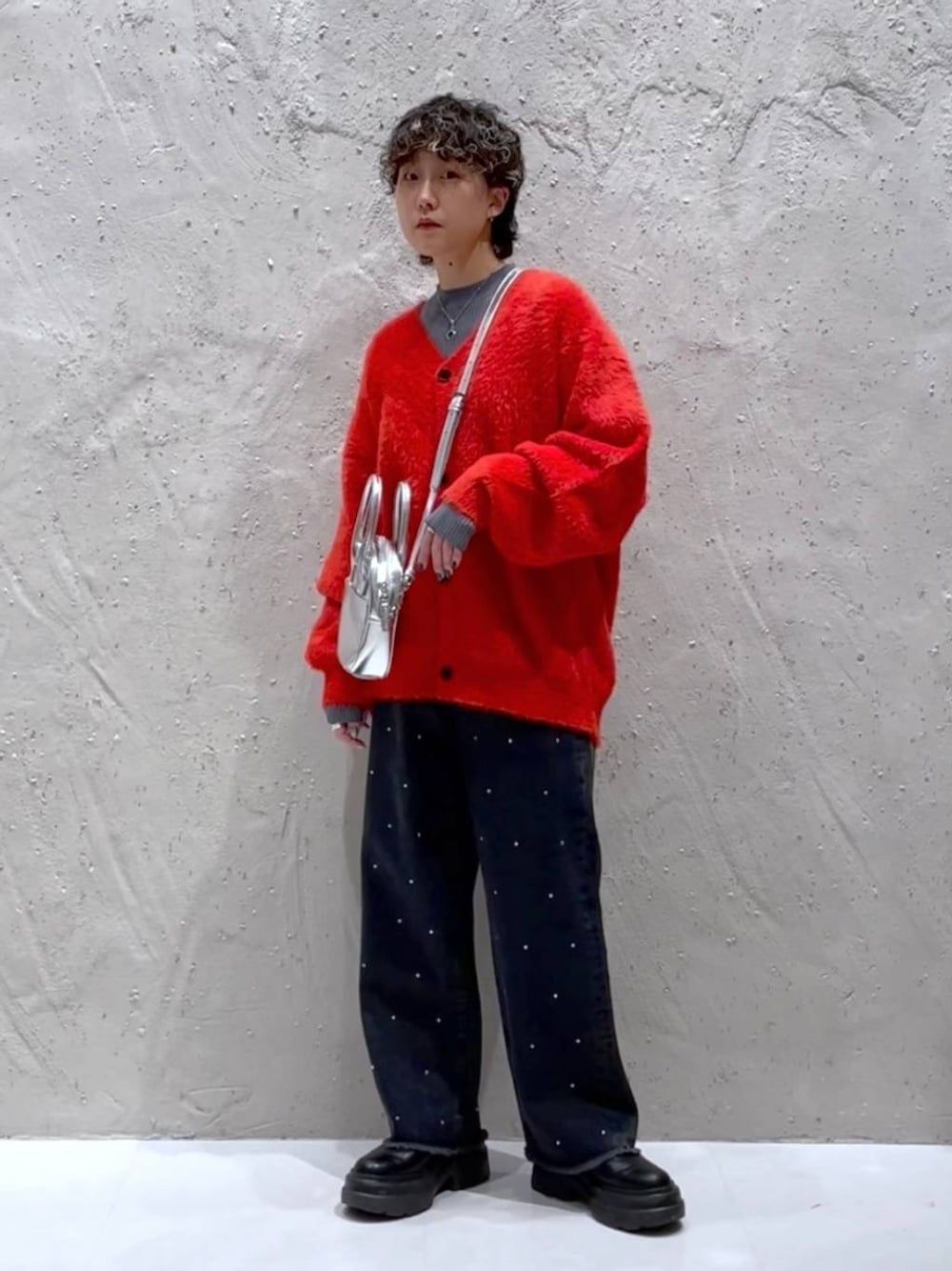 ブラック系のブーツ、シルバー系のボストンバッグ、オレンジ系のニット/セーターを着用したレディースの冬コーディネートの1枚目の写真