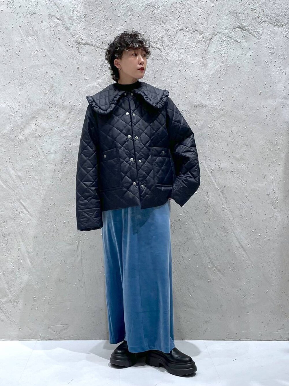 ブルー系のワンピース、ブラック系のニット/セーター、ブラック系のナイロンジャケットを着用したレディースの秋コーディネートの1枚目の写真