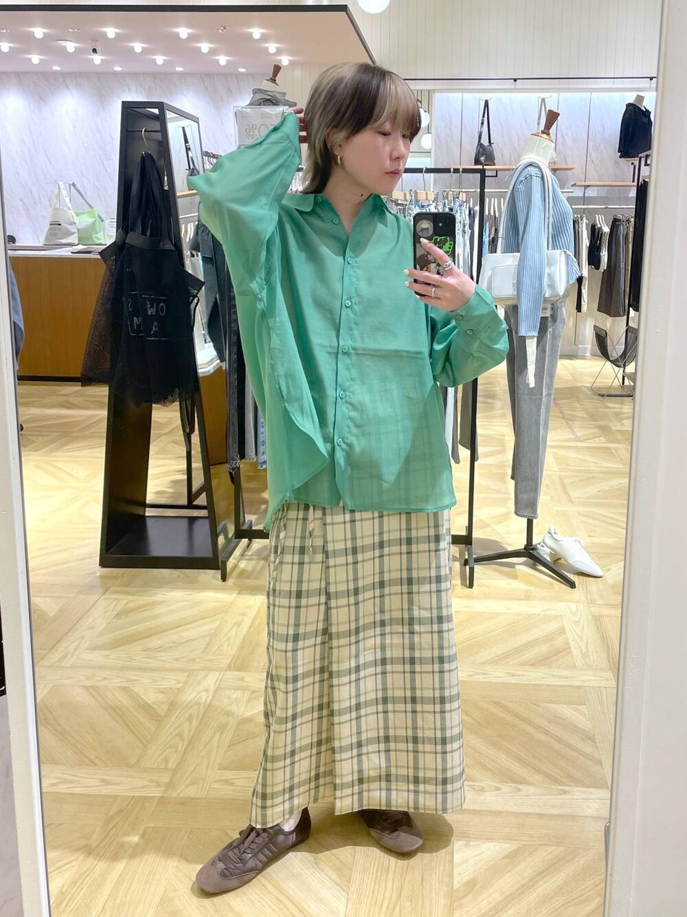 グリーン系のシャツ/ブラウス、ブラウン系のスニーカー、グリーン系のスカートを着用したレディースの春コーディネートの1枚目の写真