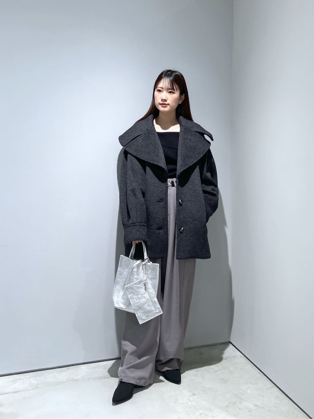 グレー系のチェスターコート、ブラック系のニット/セーター、グレー系のその他パンツを着用したレディースの冬コーディネートの1枚目の写真
