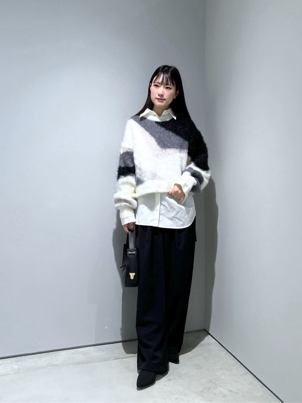 ホワイト系のニット/セーター、ホワイト系のシャツ/ブラウス、ブラック系のその他パンツを着用したレディースの冬コーディネートの1枚目の写真