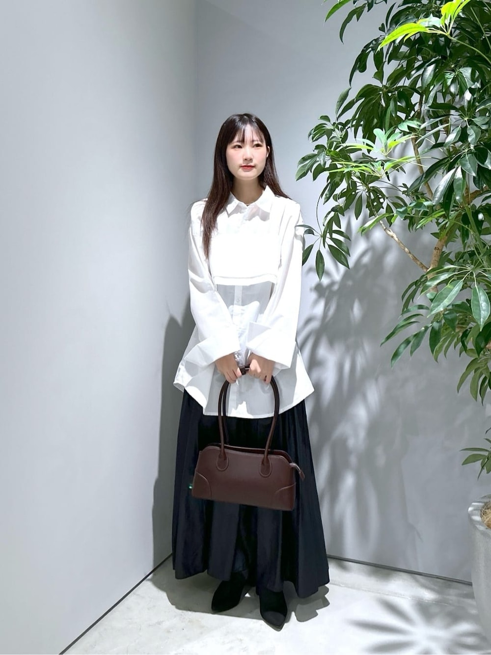 ホワイト系のシャツ/ブラウス、ブラック系のスカート、ブラウン系のショルダーバッグを着用したレディースの秋コーディネートの1枚目の写真