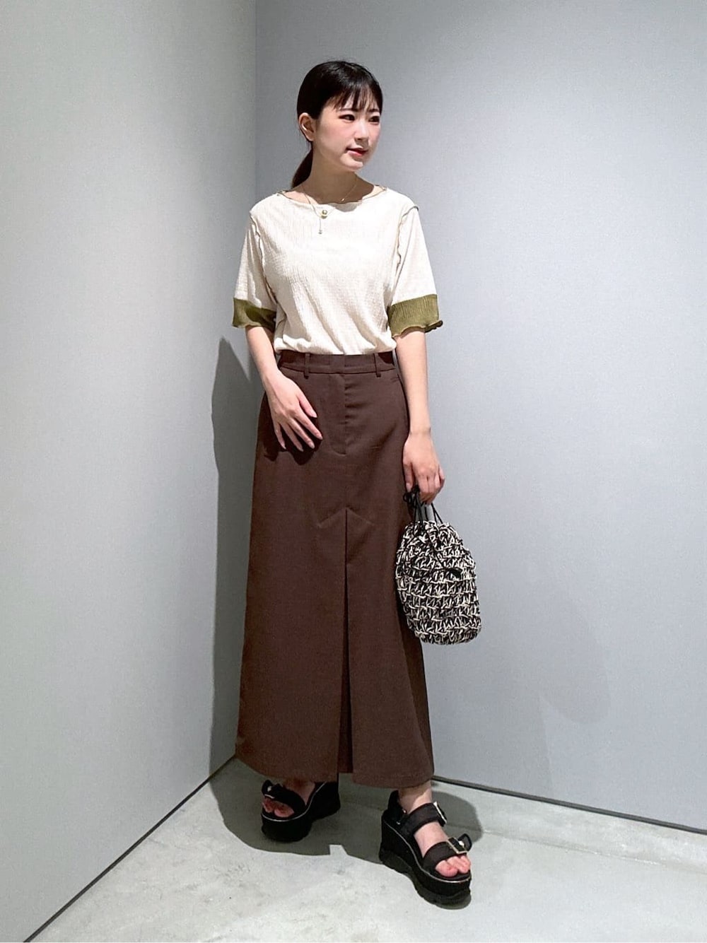 ホワイト系のTシャツ/カットソー、ブラウン系のスカート、ブラック系のハンドバッグを着用したレディースの夏コーディネートの1枚目の写真