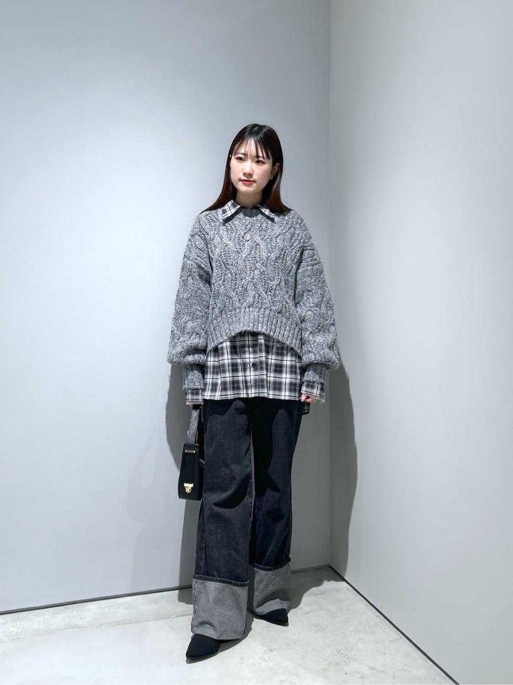グレー系のニット/セーター、ブラック系のシャツ/ブラウス、グレー系のデニムパンツを着用したレディースの冬コーディネートの1枚目の写真