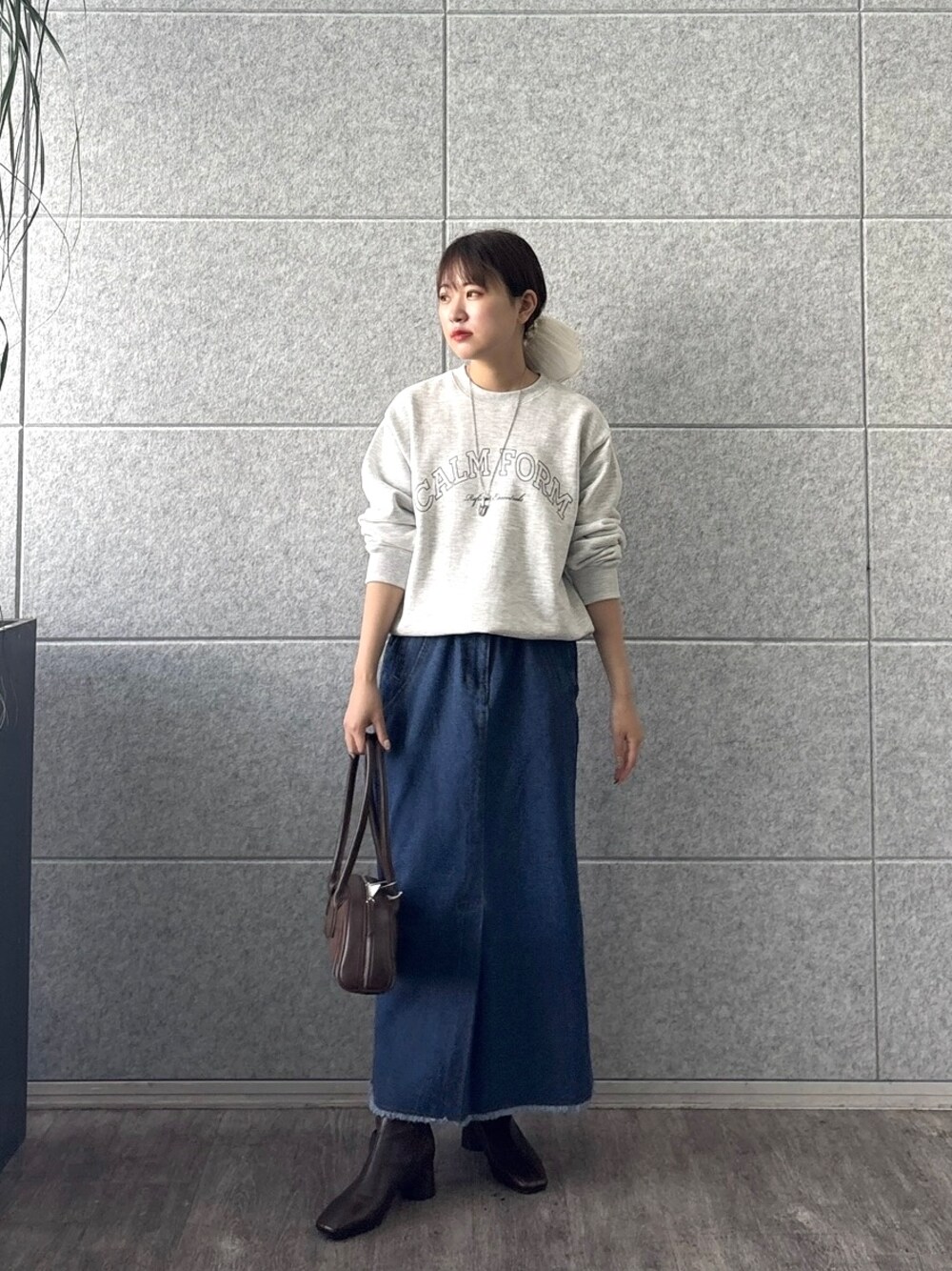 グレー系のスウェット、ブルー系のデニムスカート、シルバー系のネックレスを着用したレディースの秋コーディネートの1枚目の写真