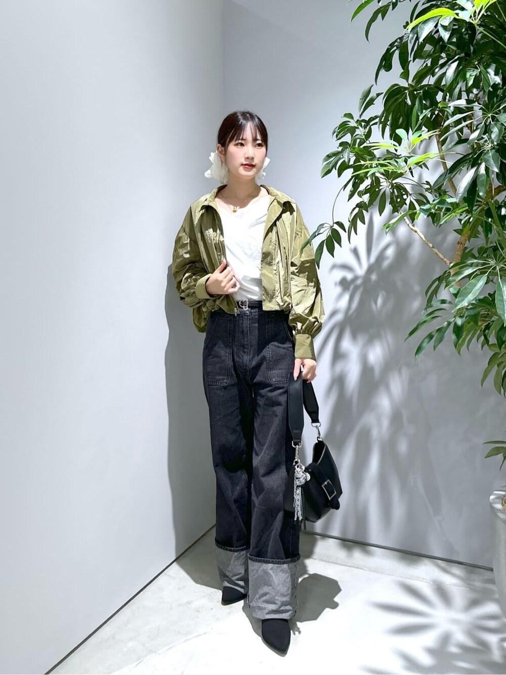 グリーン系のブルゾン、ホワイト系のTシャツ/カットソー、グレー系のデニムパンツを着用したレディースの秋コーディネートの1枚目の写真