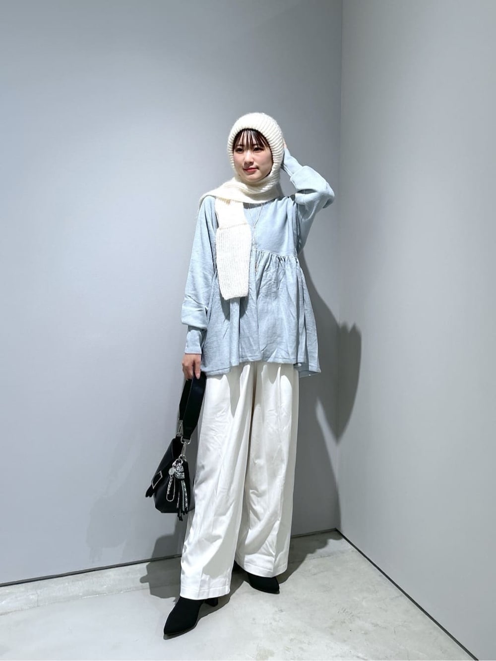 ブルー系のニット/セーター、ホワイト系のその他パンツ、ブラック系のショルダーバッグを着用したレディースの冬コーディネートの1枚目の写真