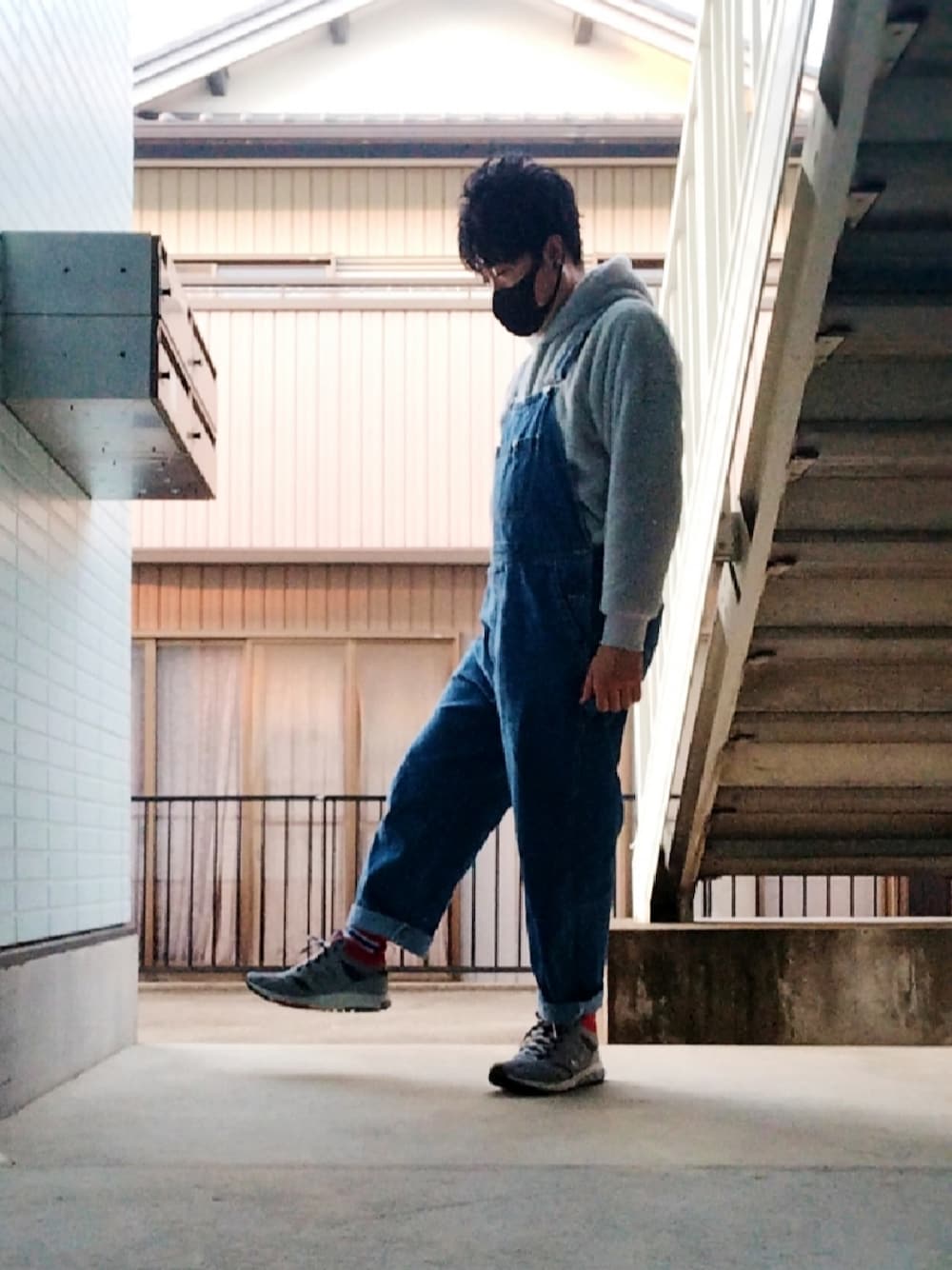 グレー系のパーカー、ブルー系のサロペット/オーバーオール、グレー系のスニーカーを着用したメンズの春コーディネートの1枚目の写真