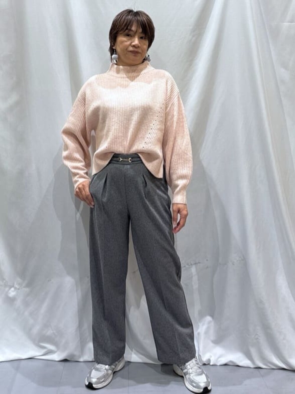 ピンク系のニット/セーター、グレー系のその他パンツ、シルバー系のスニーカーを着用したレディースの冬コーディネートの1枚目の写真