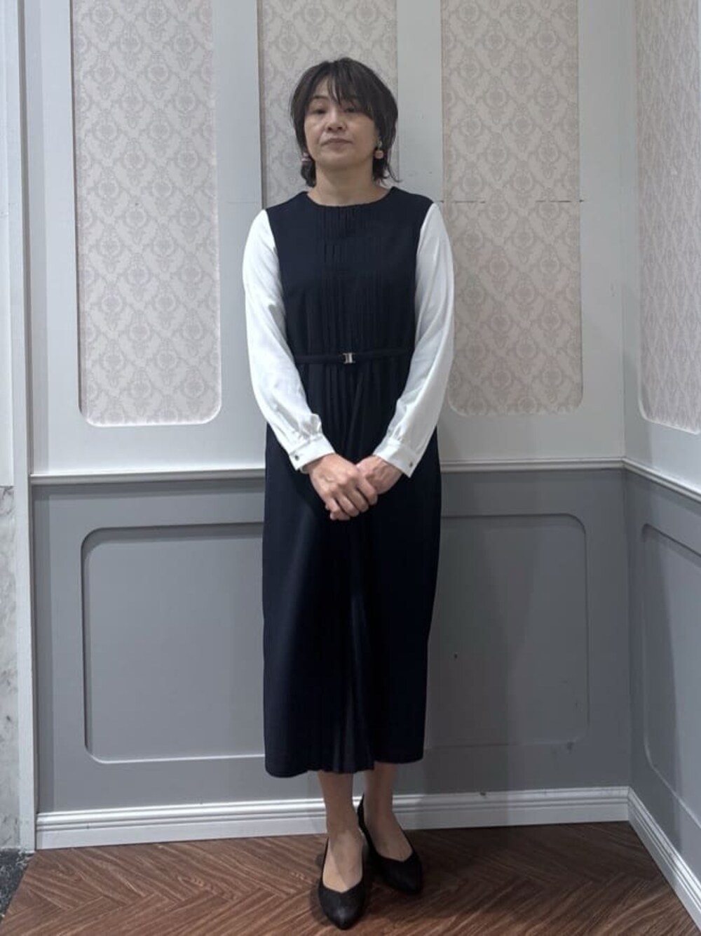 ブルー系のワンピース、ブラック系のパンプスを着用したレディースの冬コーディネートの1枚目の写真