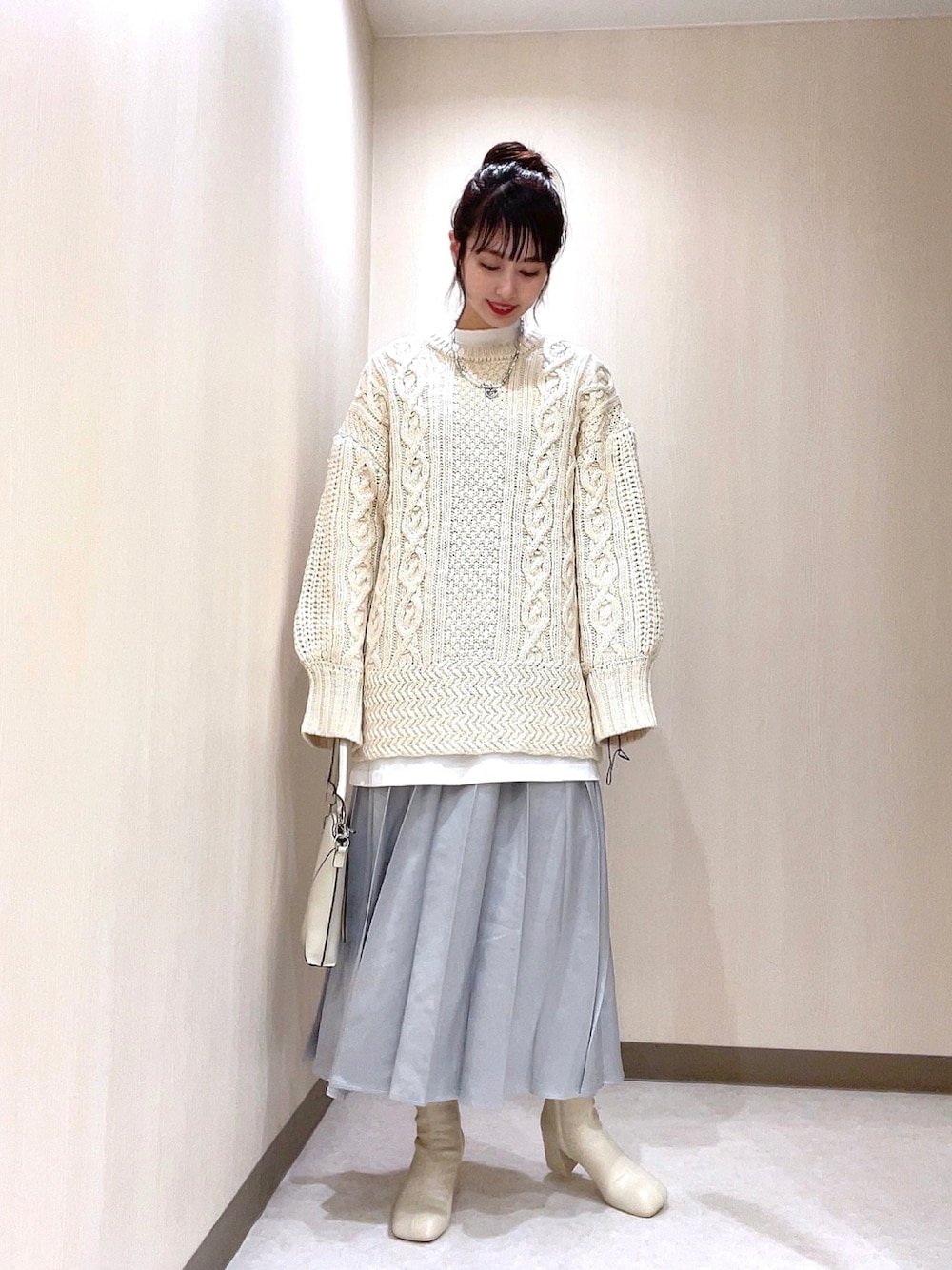 ホワイト系のニット/セーター、シルバー系のスカート、ホワイト系のブーツを着用したレディースの秋コーディネートの1枚目の写真