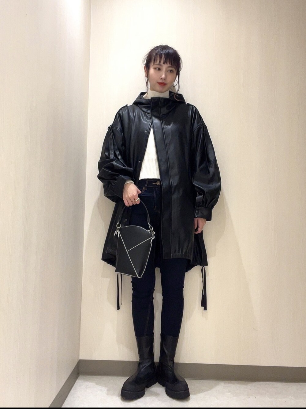 ホワイト系のニット/セーター、ブラック系のその他アウター、ブルー系のデニムパンツを着用したレディースの冬コーディネートの1枚目の写真