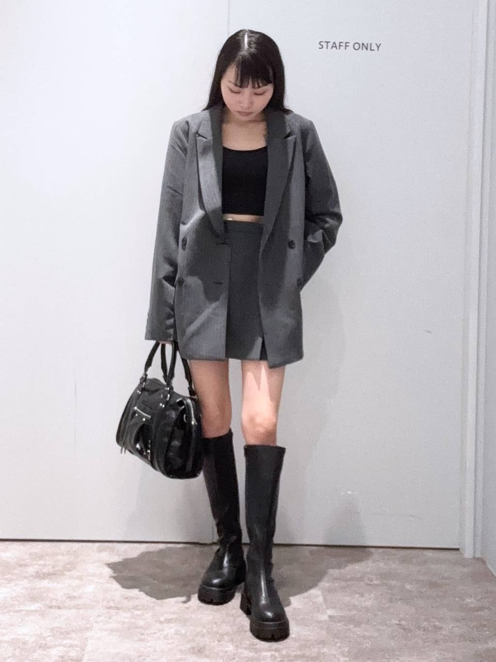 グレー系のテーラードジャケット、ブラック系のボストンバッグ、ブラック系のブーツを着用したレディースの秋コーディネートの1枚目の写真