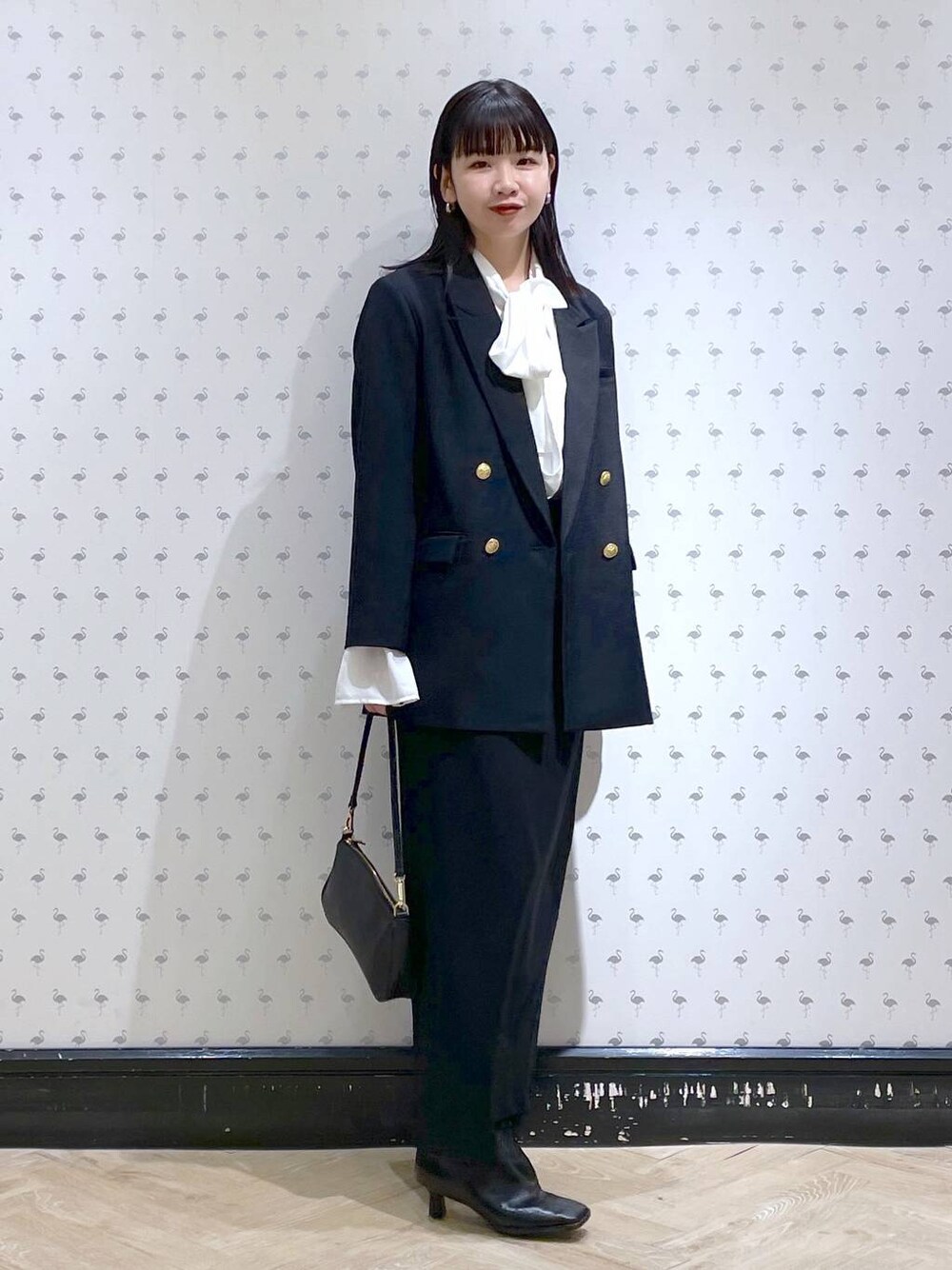 ブラック系のショルダーバッグ、ブラック系のブーツ、ブラック系のスカートを着用したレディースの冬コーディネートの1枚目の写真