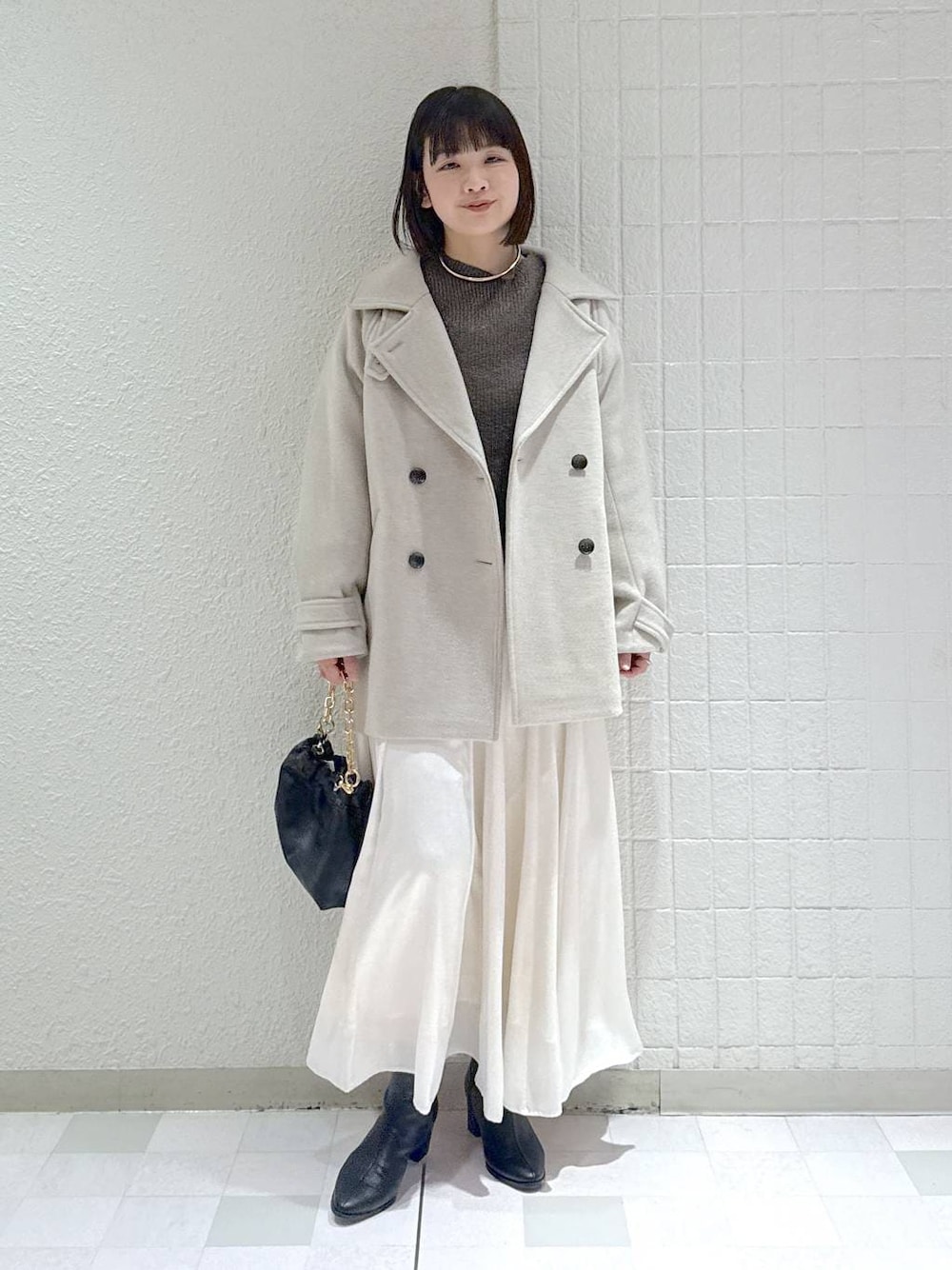 ベージュ系のピーコート、ブラック系のブーツ、ブラウン系のニット/セーターを着用したレディースの冬コーディネートの1枚目の写真