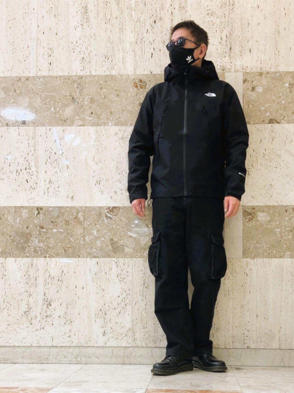 ブラック系のマウンテンパーカー、ブラック系のカーゴパンツ、ブラック系のその他シューズを着用したメンズの春コーディネートの1枚目の写真