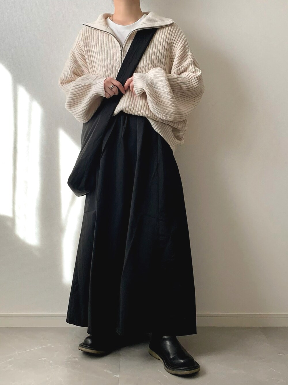 ホワイト系のニット/セーター、ブラック系のショルダーバッグ、ブラック系のブーツを着用したレディースの秋コーディネートの1枚目の写真