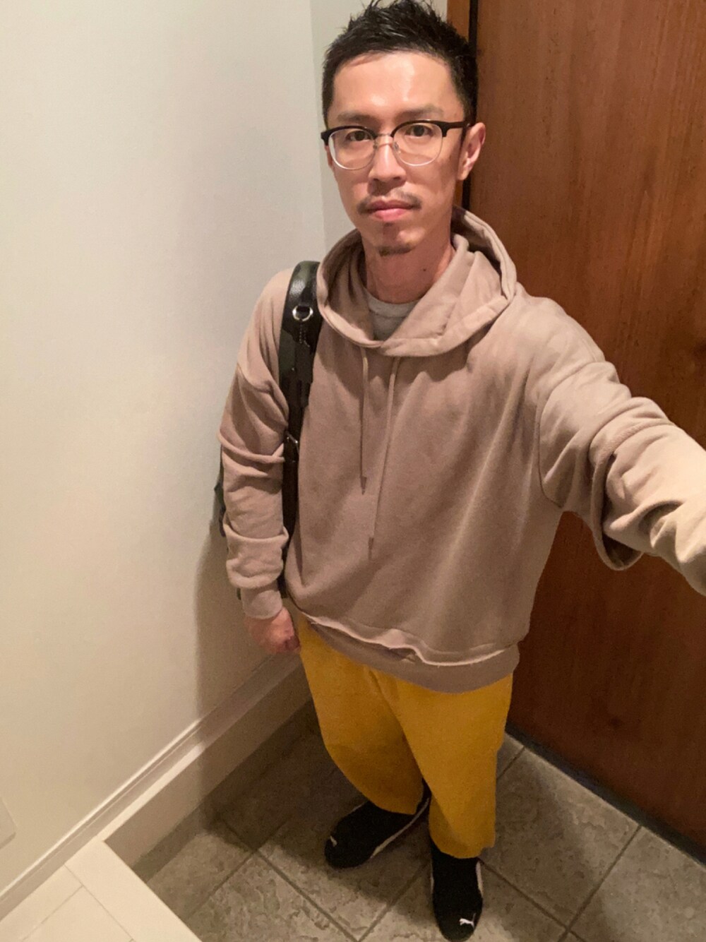 ベージュ系のパーカー、グリーン系のバックパック/リュック、イエロー系のその他パンツを着用したメンズの秋コーディネートの1枚目の写真