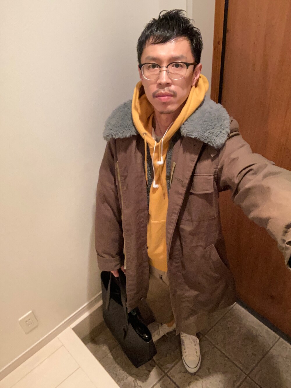 グリーン系のミリタリージャケット、イエロー系のパーカー、グリーン系のチノパンツを着用したメンズの冬コーディネートの1枚目の写真