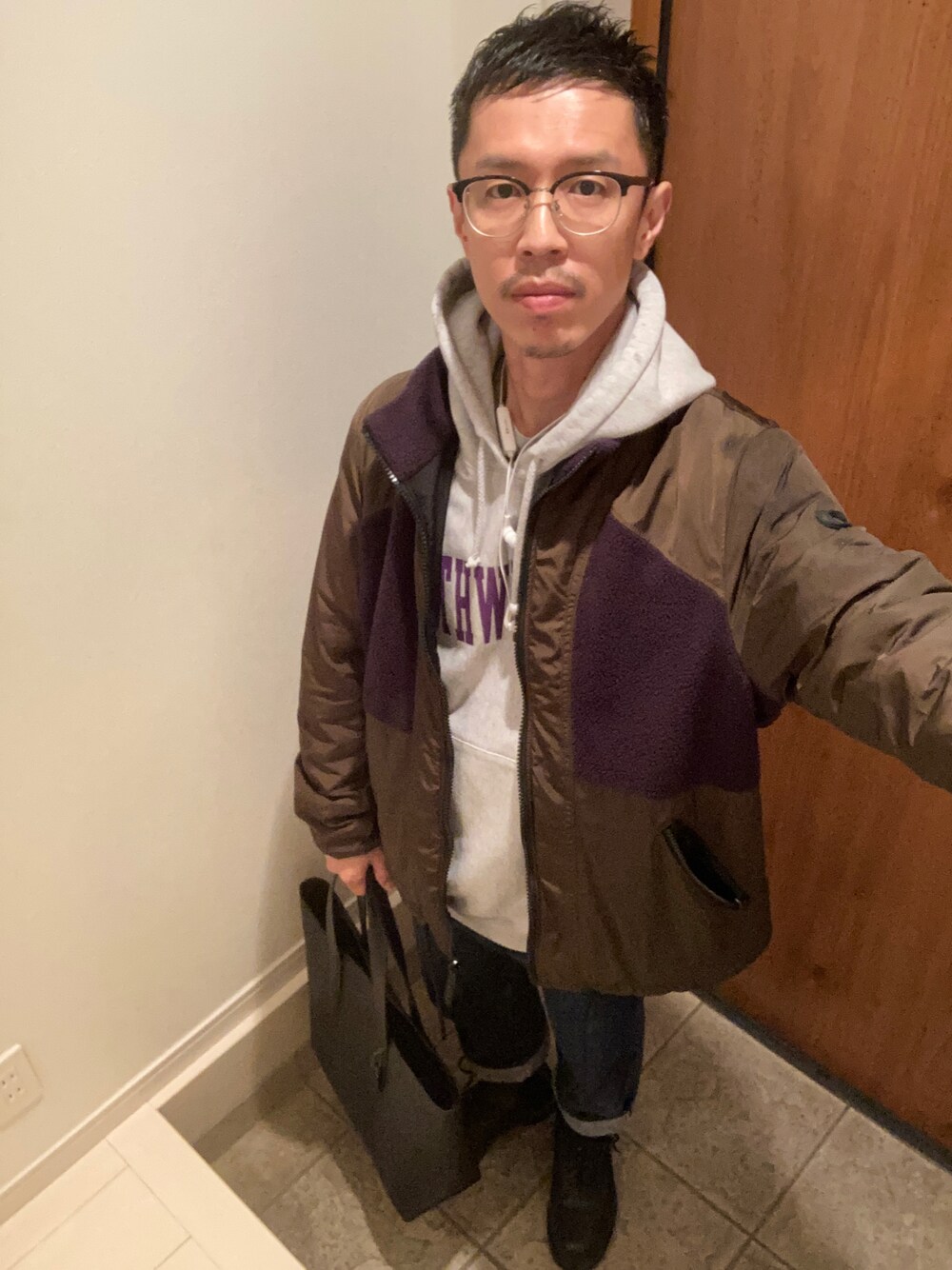 ブルー系のデニムパンツ、ブラック系のトートバッグ、ブラック系のブーツを着用したメンズの秋コーディネートの1枚目の写真