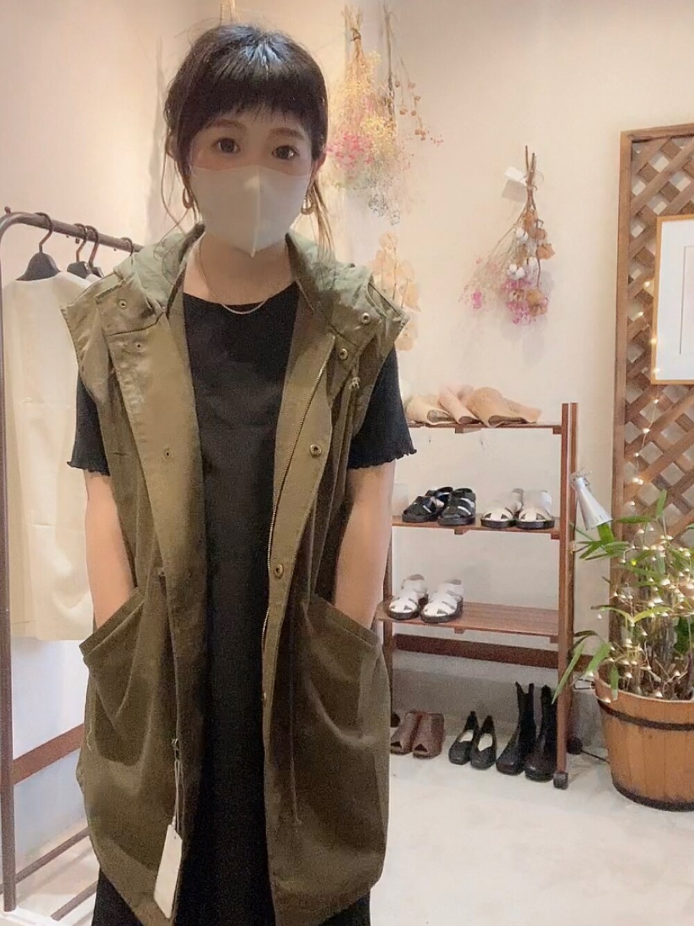 グリーン系のベスト、ブラック系のサンダル、ベージュ系のハットを着用したレディースの春コーディネートの1枚目の写真