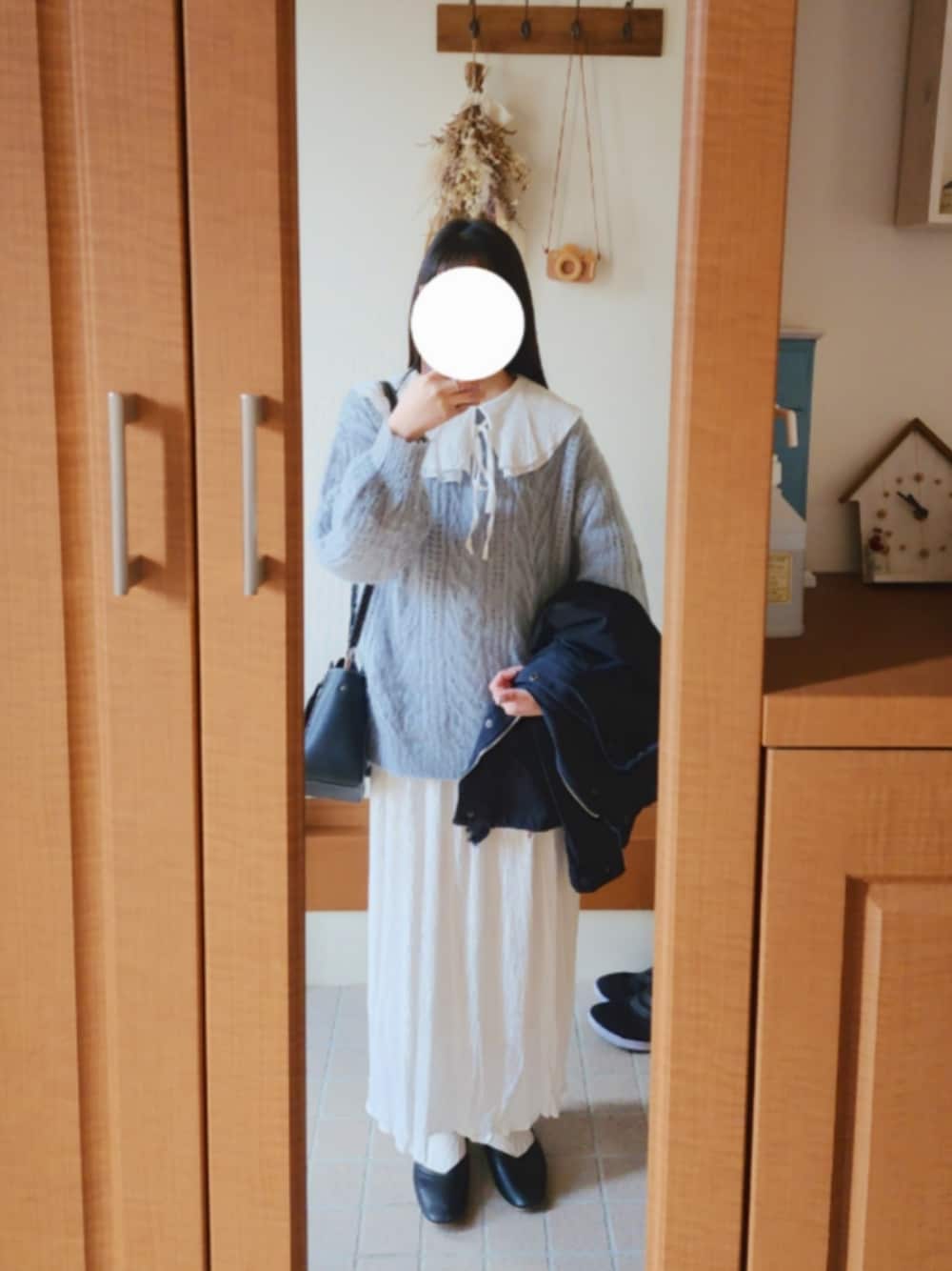 ブラック系のミリタリージャケット、ブルー系のニット/セーター、ホワイト系のシャツ/ブラウスを着用したレディースの冬コーディネートの1枚目の写真