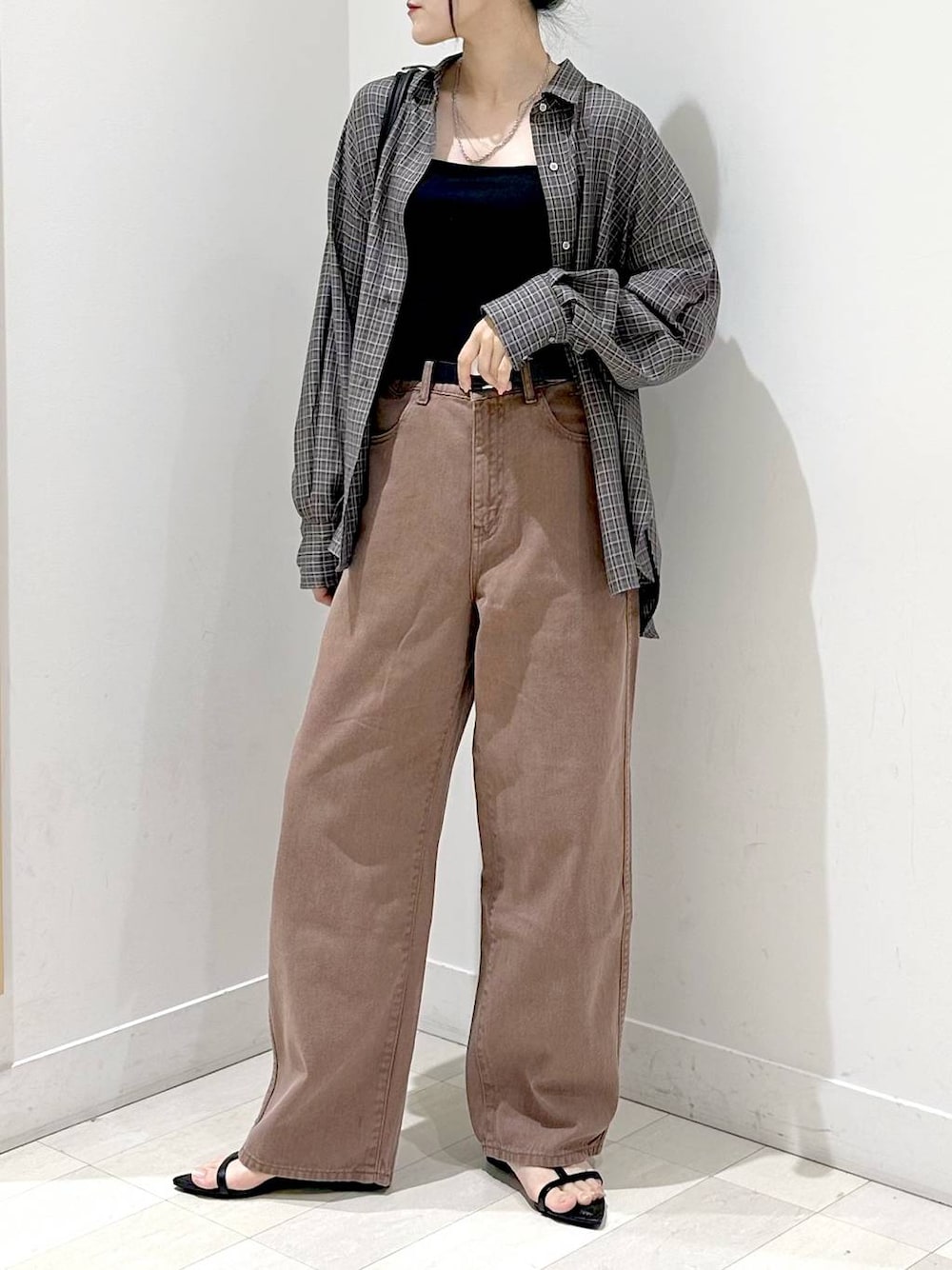 ブラック系のキャミソール、ブラック系のサンダル、ブラウン系のデニムパンツを着用したレディースの秋コーディネートの1枚目の写真