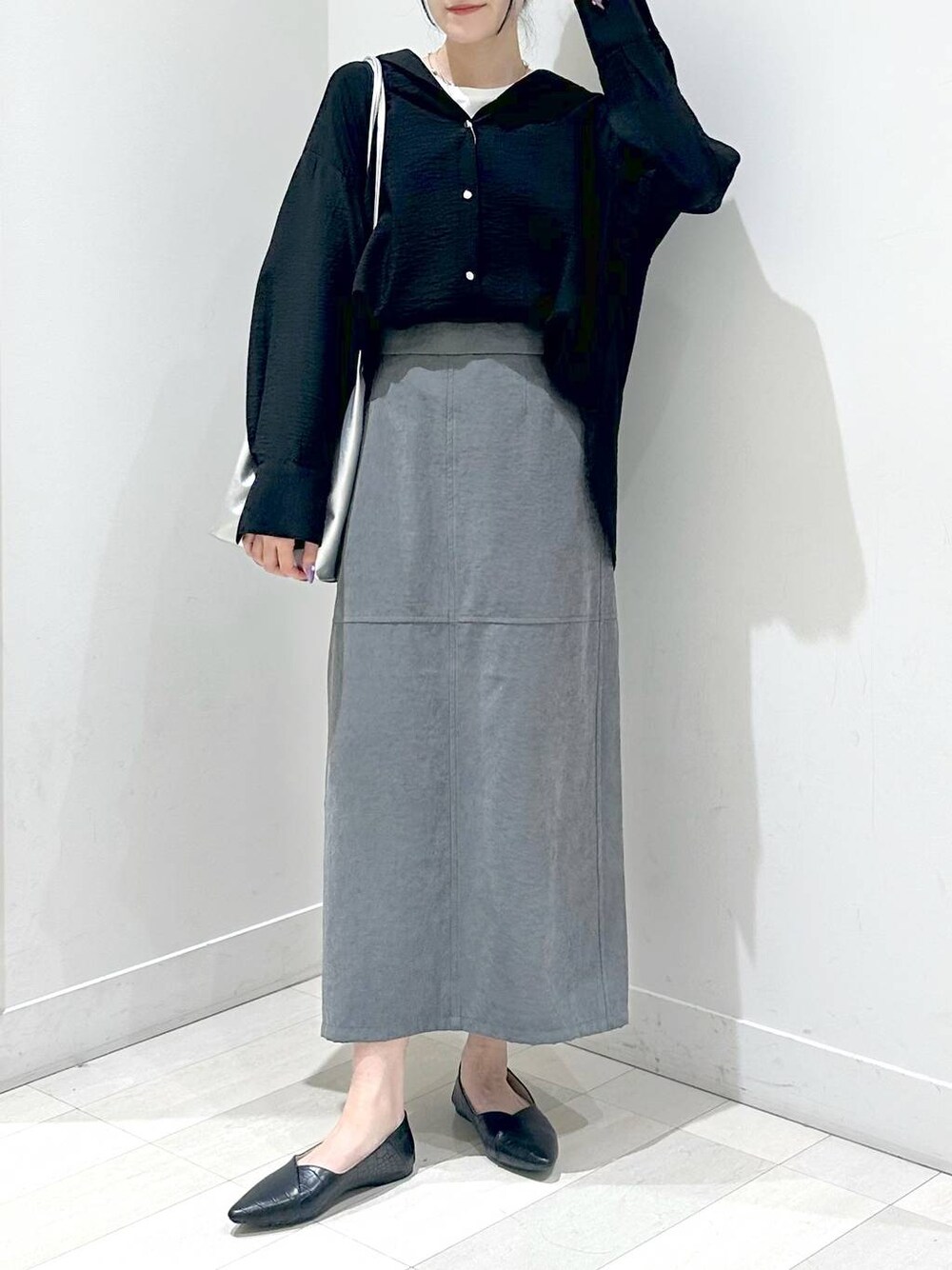 ブラック系のパンプス、ブラック系のシャツ/ブラウス、グレー系のスカートを着用したレディースの秋コーディネートの1枚目の写真