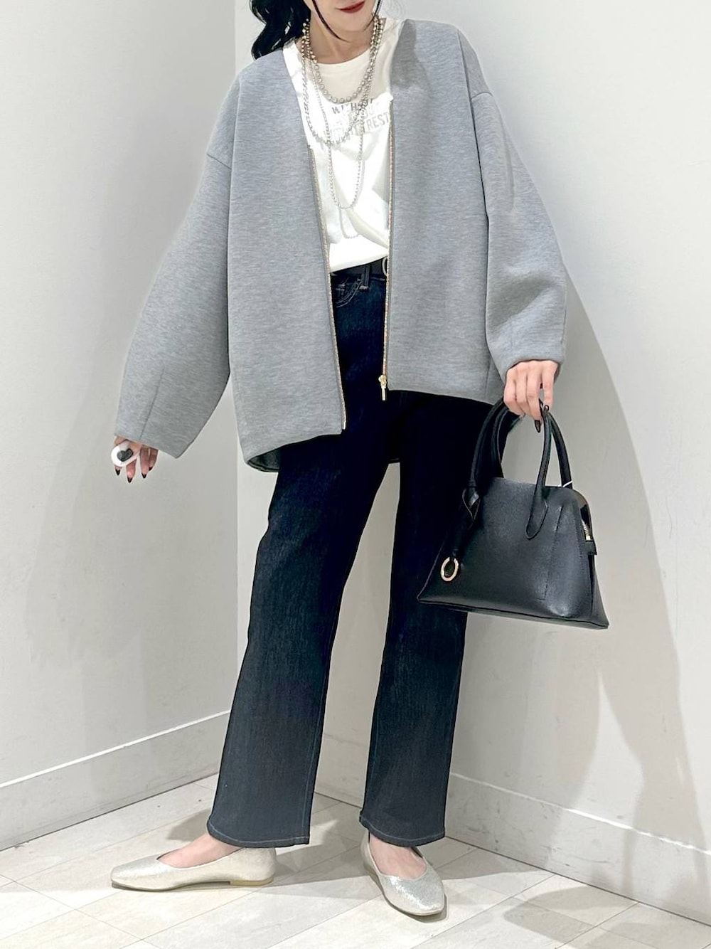 シルバー系のパンプス、ブルー系のショルダーバッグ、ブルー系のデニムパンツを着用したレディースの秋コーディネートの1枚目の写真