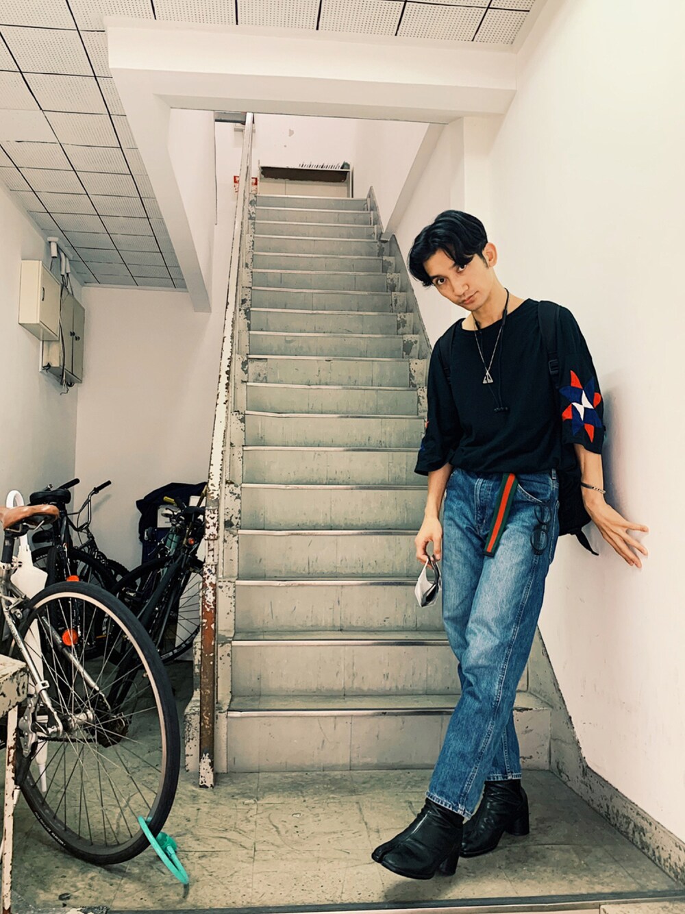 ブルー系のデニムパンツ、ブラック系のTシャツ/カットソー、ブラック系のブーツを着用したメンズの夏コーディネートの1枚目の写真